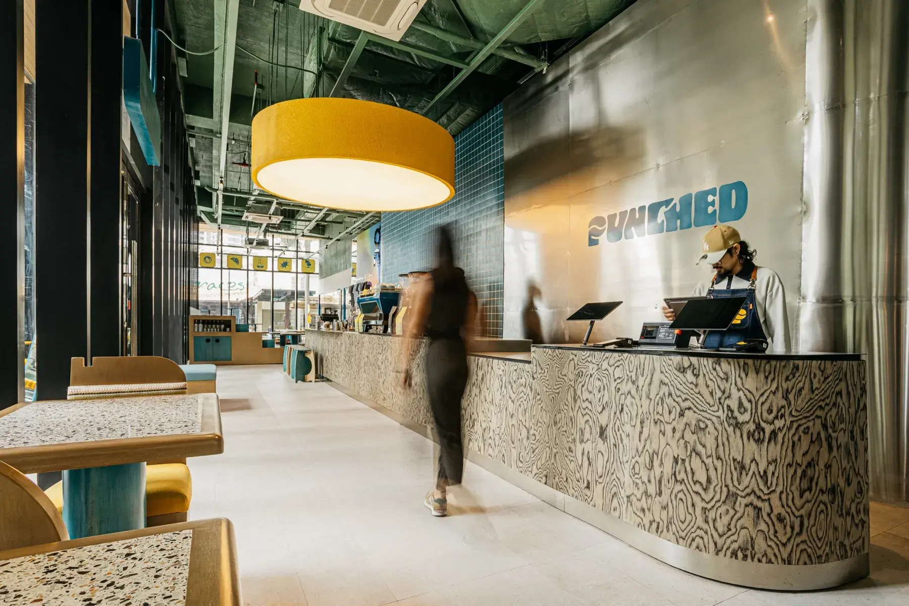 Inside Punched Coffee — barista at the counter beneath the yellow pendant light