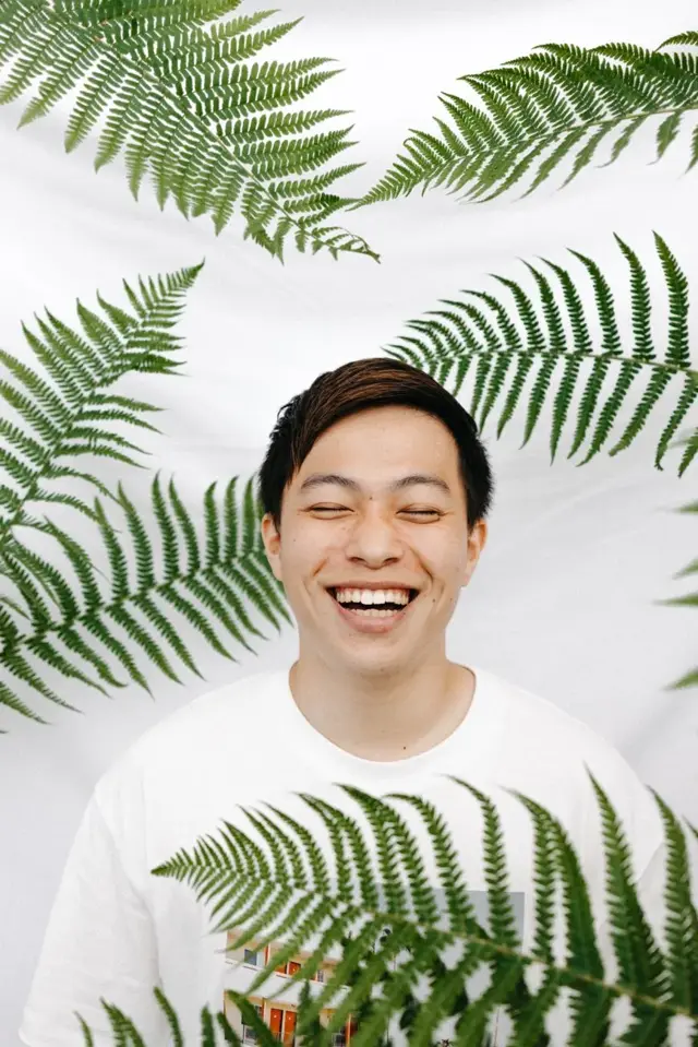 Creator smiling in front of a fern