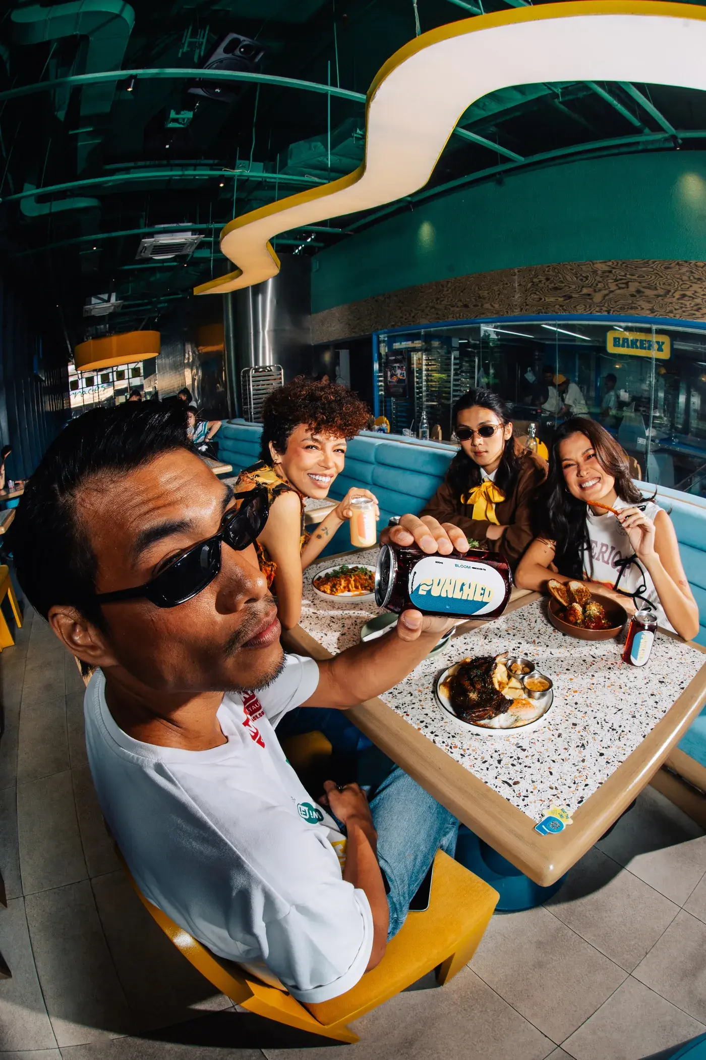 Friends at a table at Punched Coffee, one holding up a Punched can toward the camera